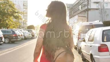 阳光年轻微笑的女人卷发看着镜头微笑走在城市的街道上。 肖像画快慢